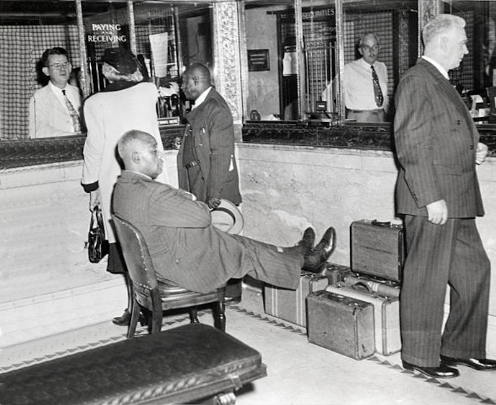 Father Divine Purchasing Hotel
10/21/1949- Newark, NJ - One of Father Divine's followerskeeps his eyes, and rests his feet, on nearly $500,000 which he and other members carried to the bank in payment for the Hotel Riviera.
